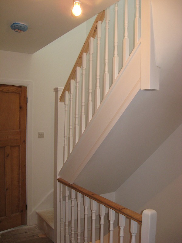 A softwood staircase for a loft conversion, painted white with feature pine handrail.