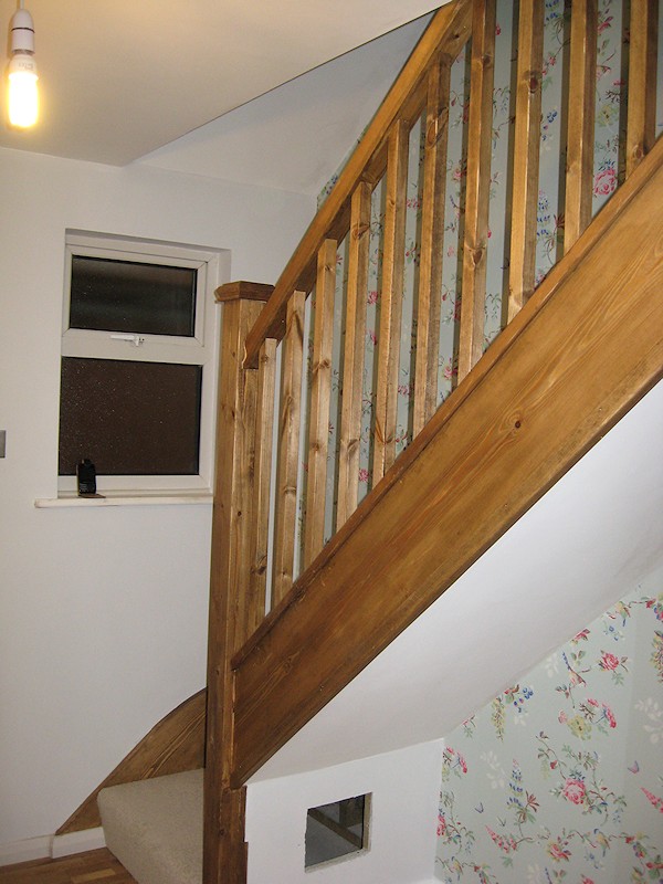A single turn winder staircase constructed in softwood and finished in dark wood stain.