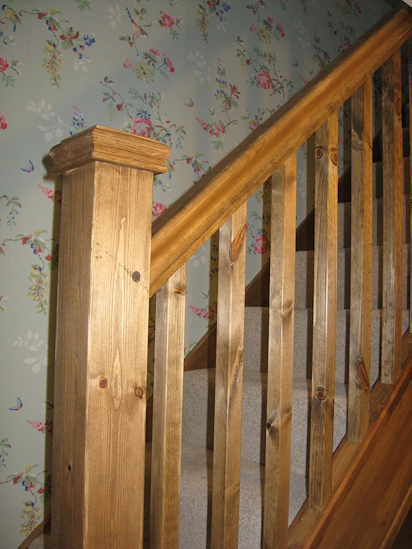 A single turn winder staircase constructed in softwood and finished in dark wood stain.