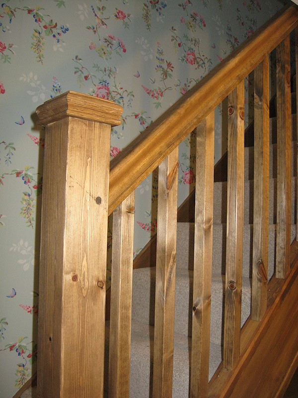 A single turn winder staircase constructed in softwood and finished in dark wood stain.