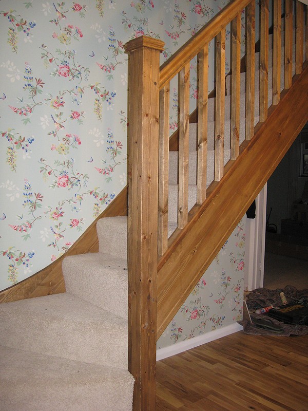 A single turn winder staircase constructed in softwood and finished in dark wood stain.