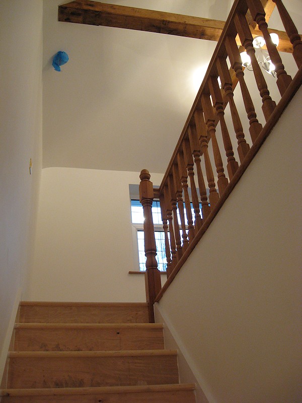 A simple straight flight staircase between enclosed walls, brought to life with oak balustrade on landing.