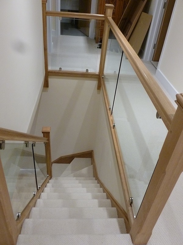 An oak single turn, winder staircase with glass balustrade.