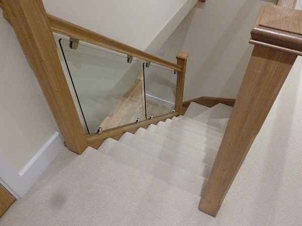 An oak single turn, winder staircase with glass balustrade.