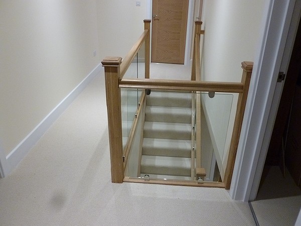 An oak single turn, winder staircase with glass balustrade.