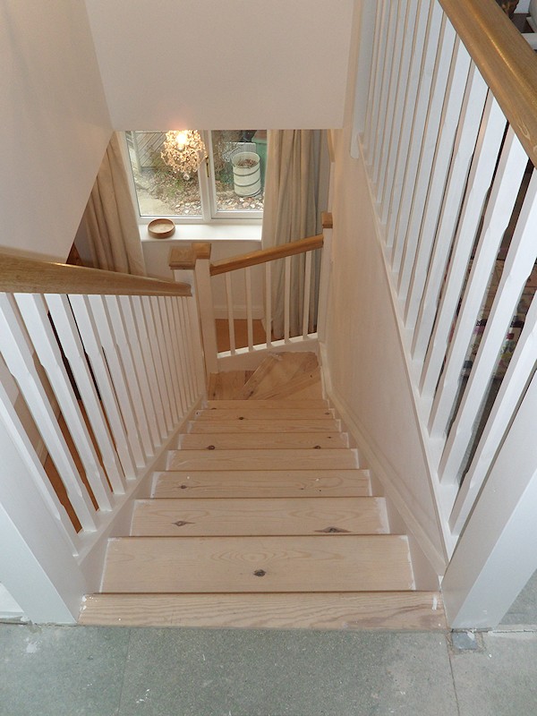 A softwood winder staircase for a loft conversion, painted white with feature oak handrail and newel caps.