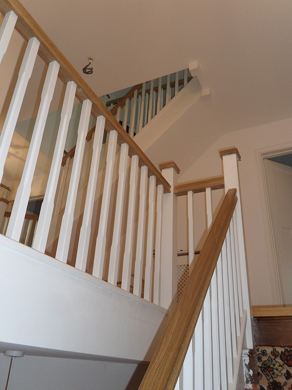 A softwood winder staircase for a loft conversion, painted white with feature oak handrail and newel caps.