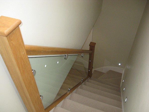 This staircase has an ultra modern feel with glass balustrade and lighting mounted above the wall string.