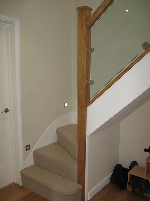 This staircase has an ultra modern feel with glass balustrade and lighting mounted above the wall string.